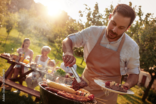 Family grilling meat on a barbecue photo
