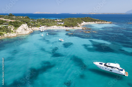 View from above, aerial picture of a yacht floating on the transparent and turquoise Mediterranean sea. Emerald Coast (Costa Smeralda) in Sardinia, Italy. © Travel Wild