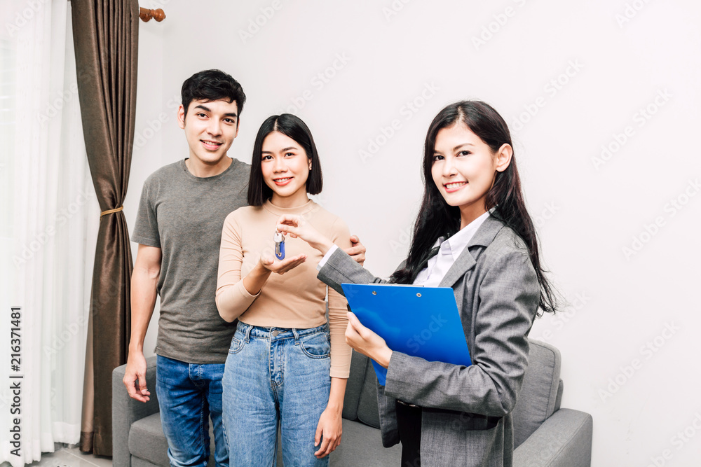 Fototapeta premium Real estate agent giving keys for couple at a house for sale.business and real estate concept