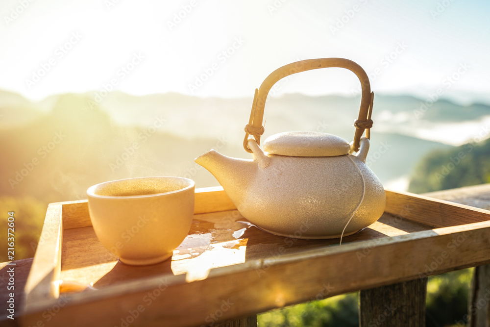 Hot tea ,cup, tea pot at cold morning with sunrise in the foggy mountains  Stock Photo