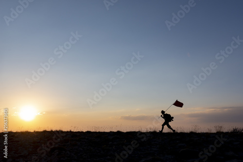 Brave mountaineer carrying the flag on top © emerald_media