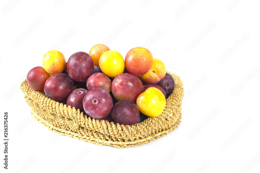 Plum fruit in straw wicker bowl isolated on white Plum fruit in straw wicker bowl isolated on white
