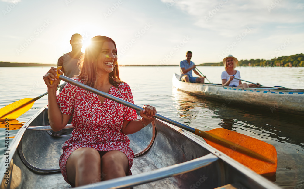 Obraz premium Smiling couple canoeing with friends on a late summer afternoon