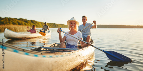 Fotografie Smiling woman canoeing with friends on a lake in summer