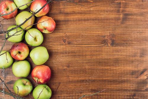 Sweet juicy red and green apples with branches on wooden background. Free copy space for text. Top view, flat lay