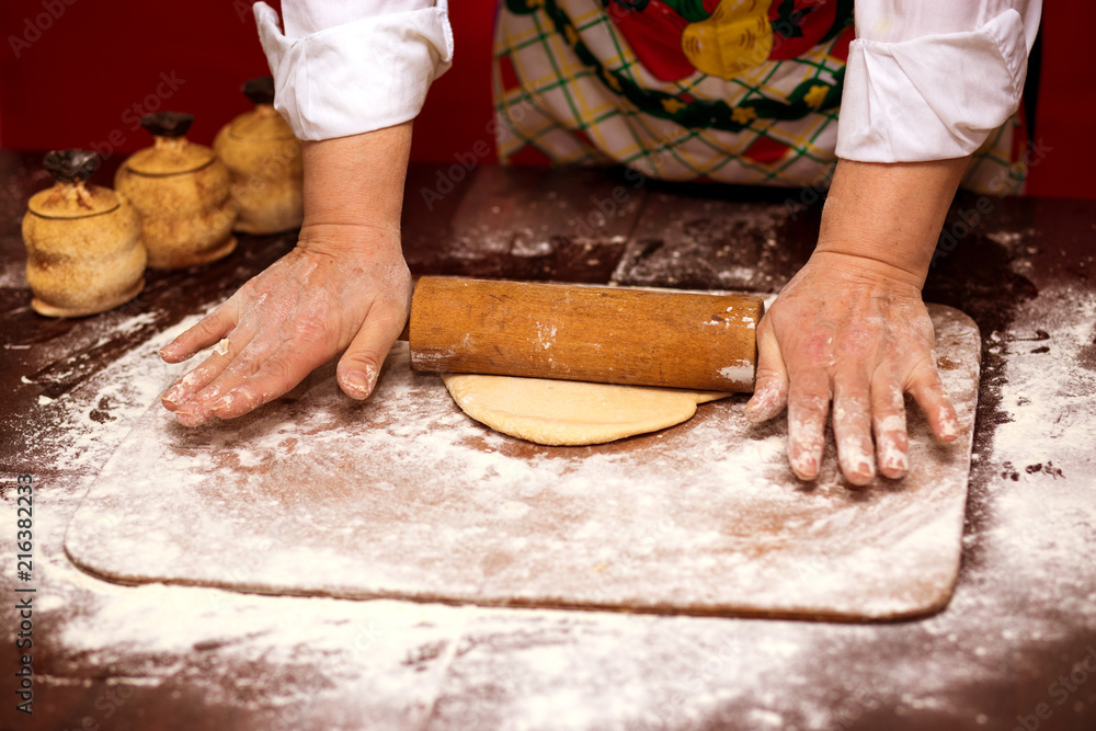Close up of female baker hands kneading dough and making bread with a rolling pin. Cooking Process Concept 