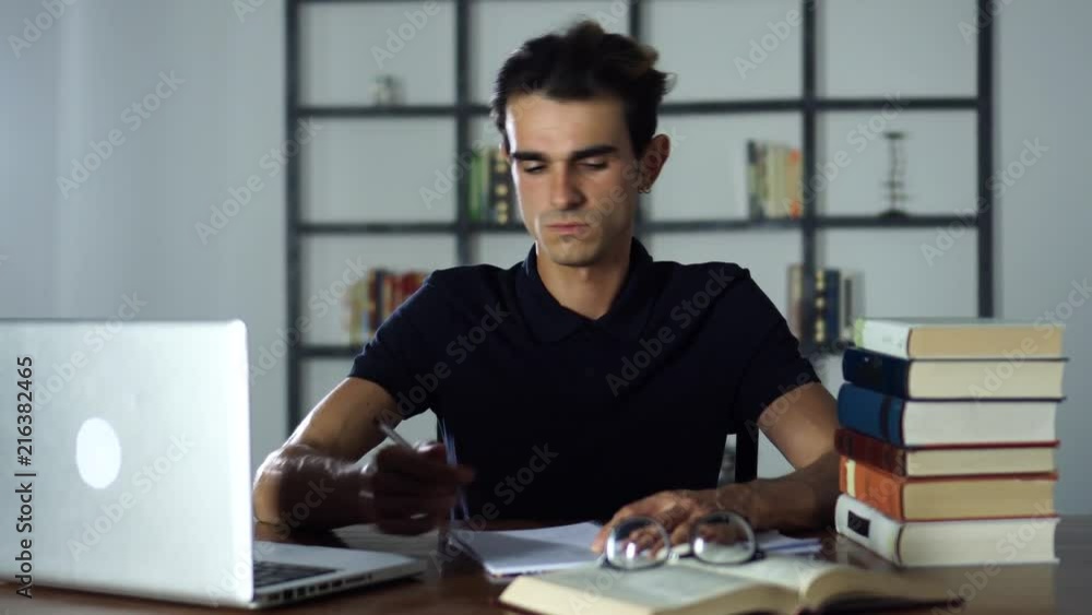 Man Studying At Home, Searching the Internet on a Laptop, Writting in notebook, Readind. New Technology in Studying, Digital Device, Education Man Studying At Home, Searching the Internet on a Laptop, Writting in notebook, Readind. New Technology in Studying, Digital Device, Education