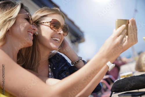 Trendy girls taking selfie pictures with smartphone