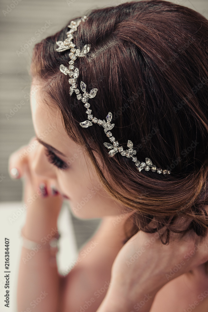 Portrait of young brunette bride woman in dressing room with wedding jewelry and dress