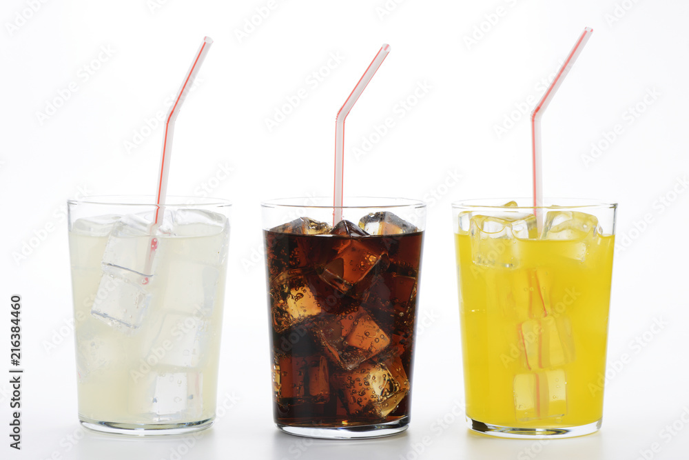 Refrescos de cola, naranja y limón en vaso con pajita sobre fondo blanco Refrescos de cola, naranja y limón en vaso con pajita sobre fondo blanco