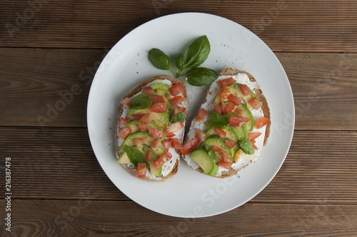 Homemade Healthy Toast sandwich with Avocado, cheese cream and tomatoe on wooden board. Breakfast healthy food.