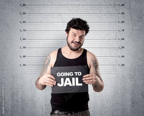 Caugth offender in front of a wall with table in his hand.