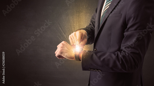 Businessman wearing smartwatch with shiny rays on it.