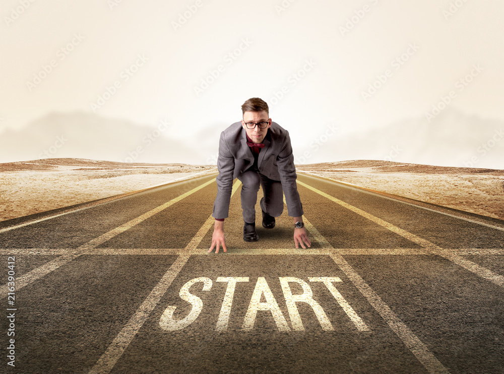 Young determined businessman kneeling before start line Young determined businessman kneeling before start line