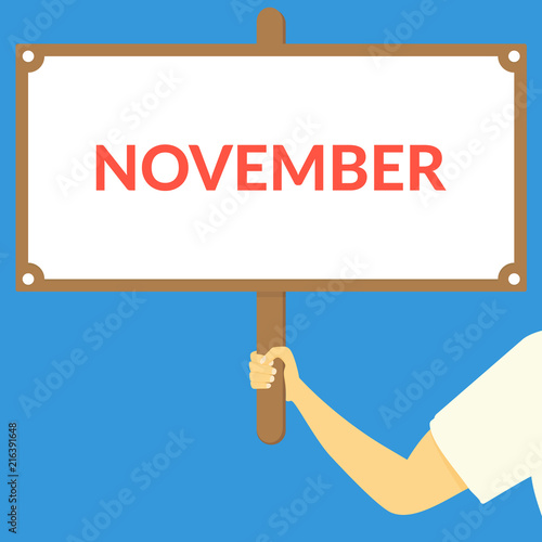 NOVEMBER. Hand holding wooden sign