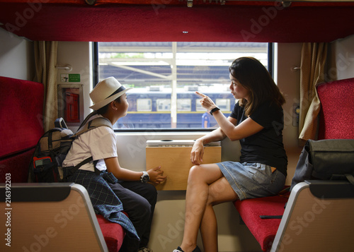 Mother and son looking through a train window as they enjoy a days travel at Thailand
