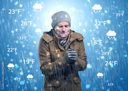 Young man freezing in warm clothing with weather condition and forecast concept
