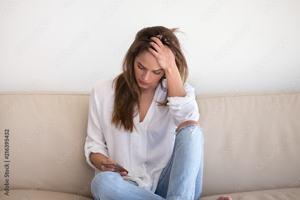 Sad young woman desperately looking at smartphone screen, waiting call from boyfriend or lover, depressed woman holding phone, broken after message received. Concept of loneliness, breaking up Sad young woman desperately looking at smartphone screen, waiting call from boyfriend or lover, depressed woman holding phone, broken after message received. Concept of loneliness, breaking up