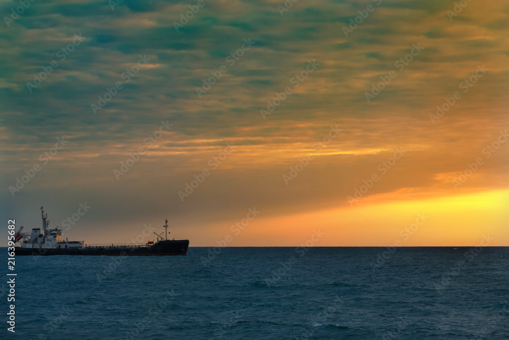 Fishing boat in the open sea on the horizon during sunset