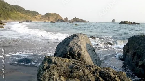 Tracking shot to the left as waves crash on the beach at Boardman State Park in Brookings, Oregon photo