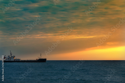 Fishing boat in the open sea on the horizon during sunset © SerPak