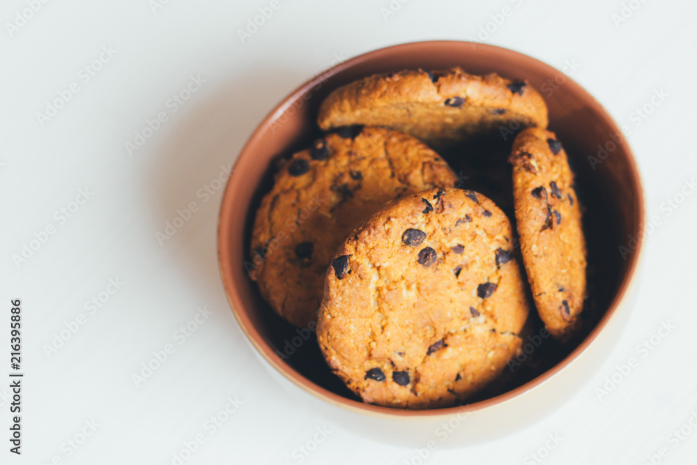 Chocolate cookies in a brown bowl on a white background, top view