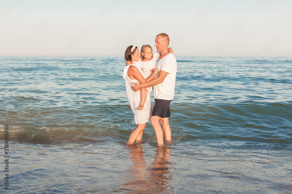 Parents with a daughter stand on the seashore.