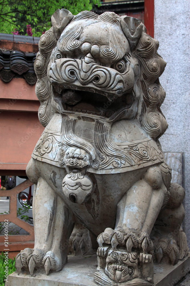 gray lion stone carving at the entrance of a temple