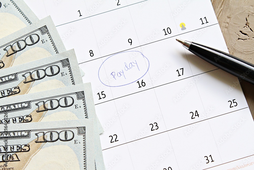 Business, finance, savings money, wages, payroll or accounting concept : Calendar with blue marker circle in word payday and American dollars cash money for remind Business, finance, savings money, wages, payroll or accounting concept : Calendar with blue marker circle in word payday and American dollars cash money for remind