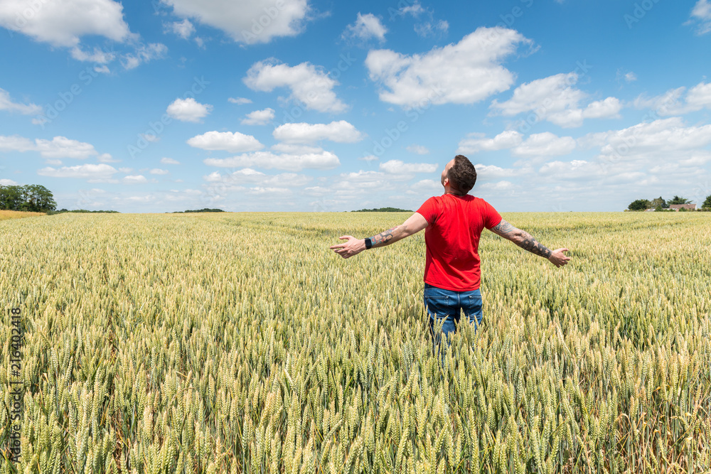 Young Man Standing in a Wheatfield with his Arms Stretched Out