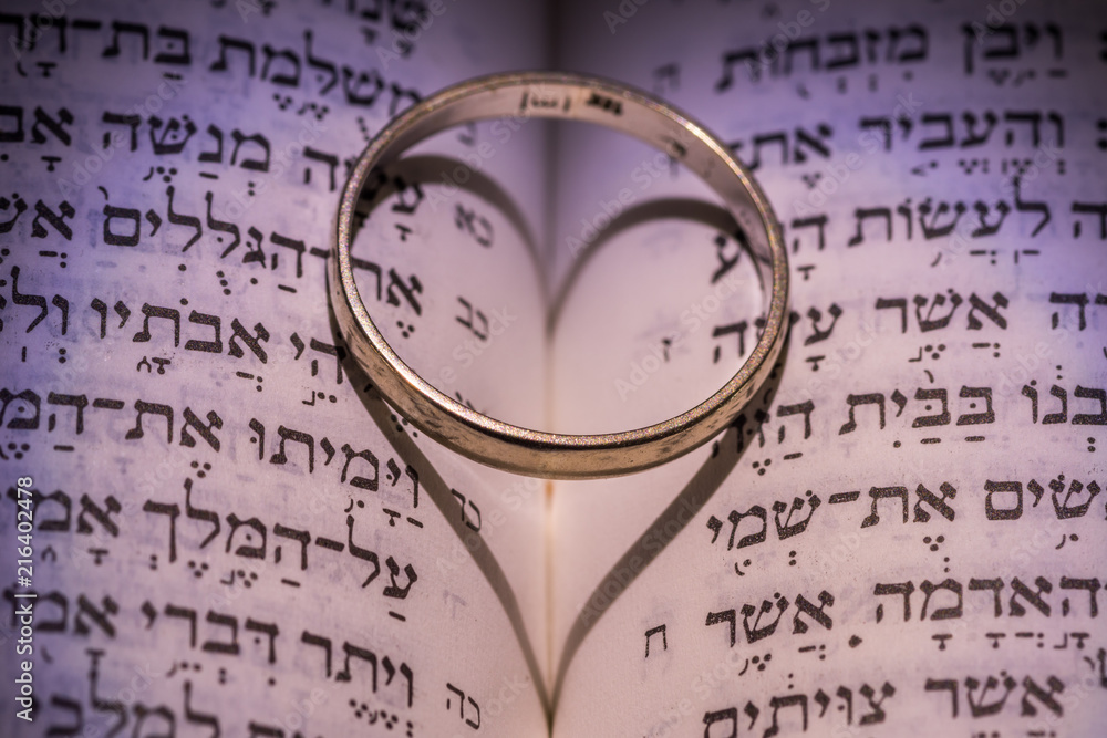 Close up of the Hebrew Jewish bible with a weeding ring creating a heart shape shadow Close up of the Hebrew Jewish bible with a weeding ring creating a heart shape shadow