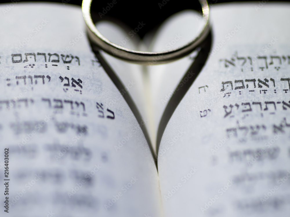 Close up of the Hebrew Jewish bible with a weeding ring creating a heart shape shadow Close up of the Hebrew Jewish bible with a weeding ring creating a heart shape shadow