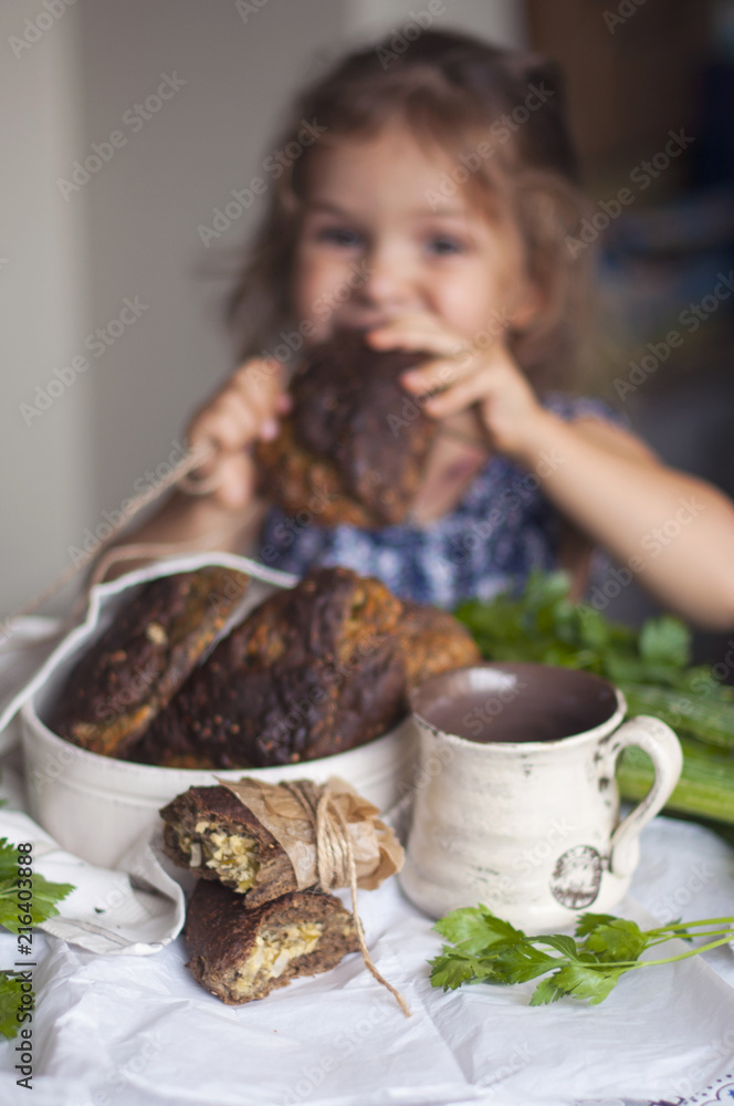 A little girl is eating pies in the living room. Delicious homemade pastries and happy baby A little girl is eating pies in the living room. Delicious homemade pastries and happy baby