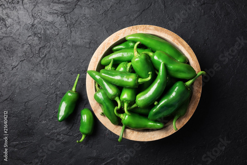Photos Green jalapeno hot pepper in wooden plate closeup