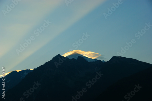 tetnuldi mountain silhouette. sunbeams and clouds at dawn photo