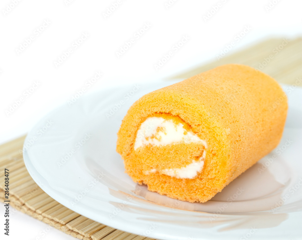 orange cake roll on white plate on wooden mat. orange cake roll on white plate on wooden mat.