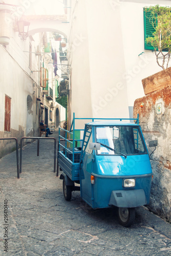 old three-wheeled car parked on narrow street