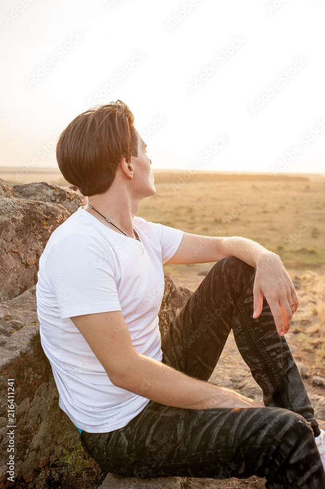 guy sits on a rock and watches the sunset guy sits on a rock and watches the sunset