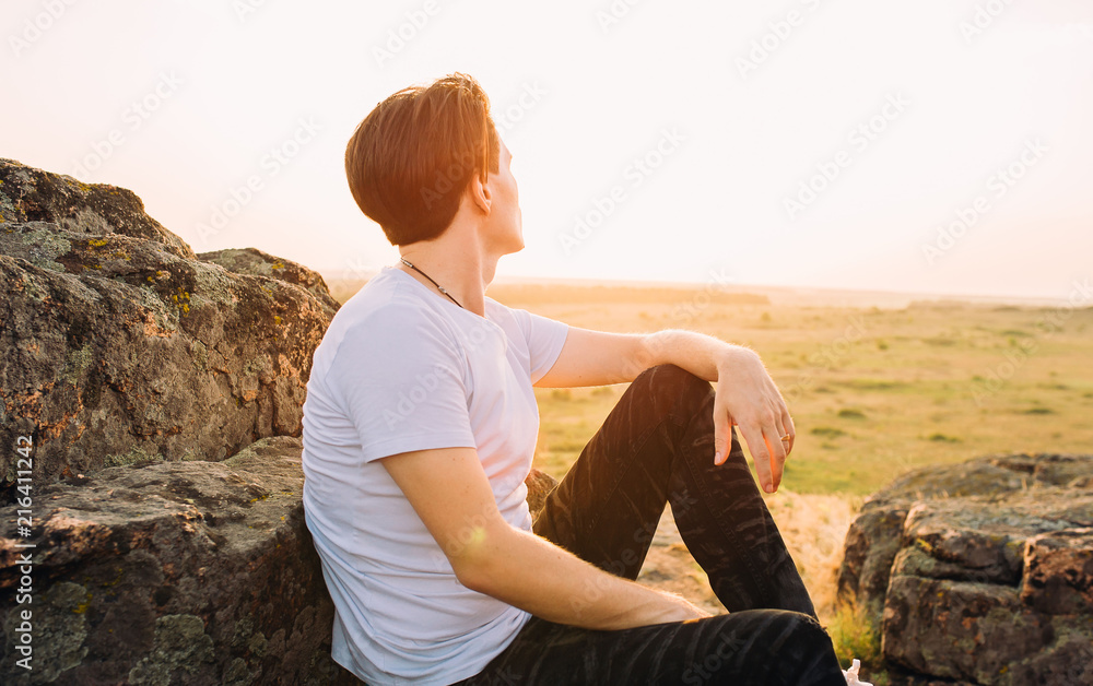 guy sits on a rock and watches the sunset guy sits on a rock and watches the sunset