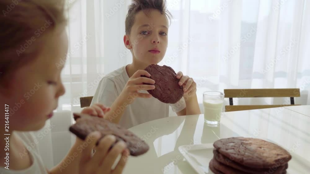 Two boy eating homemade chocolate cookies with milk at kitchen Two boy eating homemade chocolate cookies with milk at kitchen