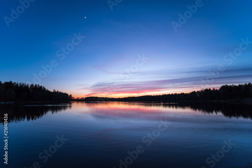 Sunset just befor night at a lake with the moon in the sky