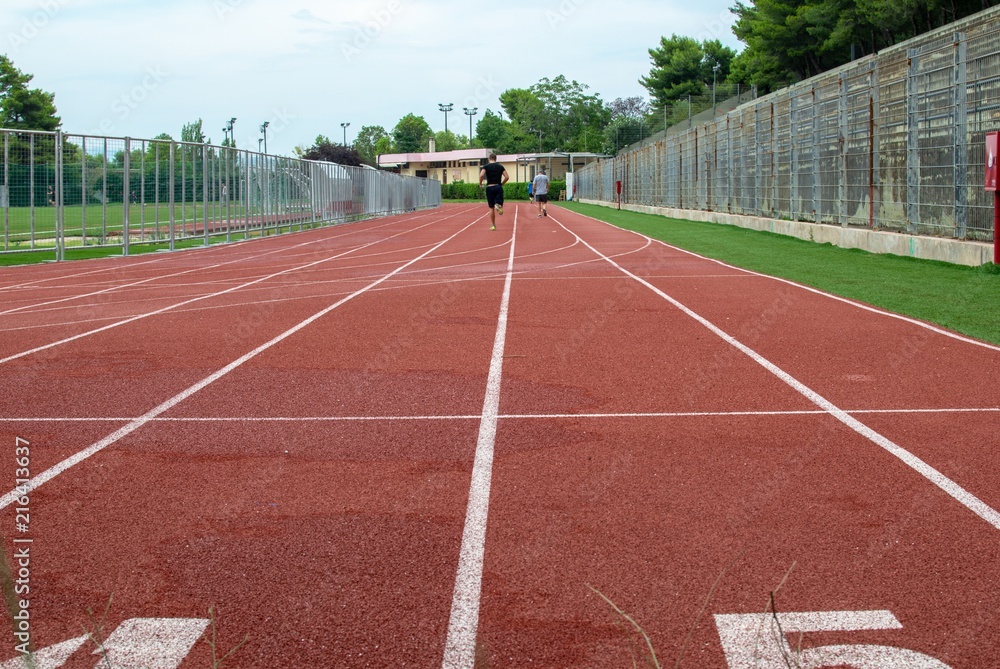Fototapeta premium People running in the tartan of an open stadium.