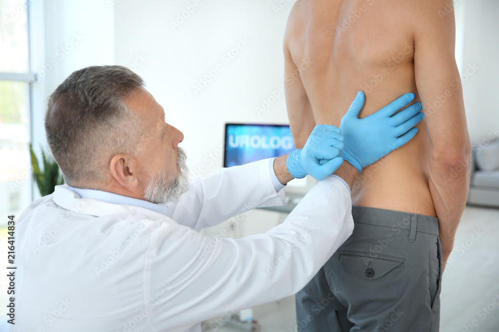 Urologist in gloves examining young patient in clinic Urologist in gloves examining young patient in clinic