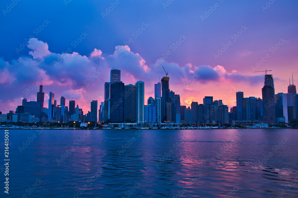 Colorful sunset reflecting onto clouds, Lake Michigan, and Chicago skyline during summer recreation season.