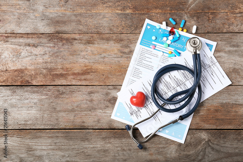 Flat lay composition with stethoscope and pills on wooden background. Cardiology service photo