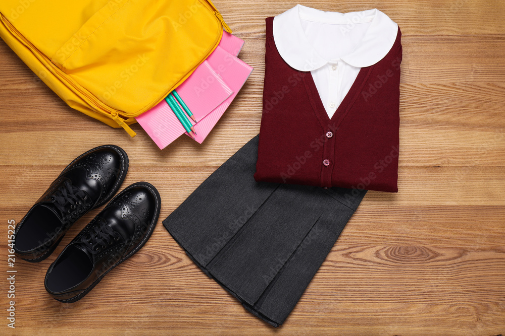 School uniform for girl and stationery on wooden background School uniform for girl and stationery on wooden background