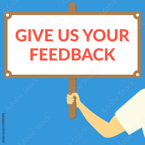 GIVE US YOUR FEEDBACK. Hand holding wooden sign