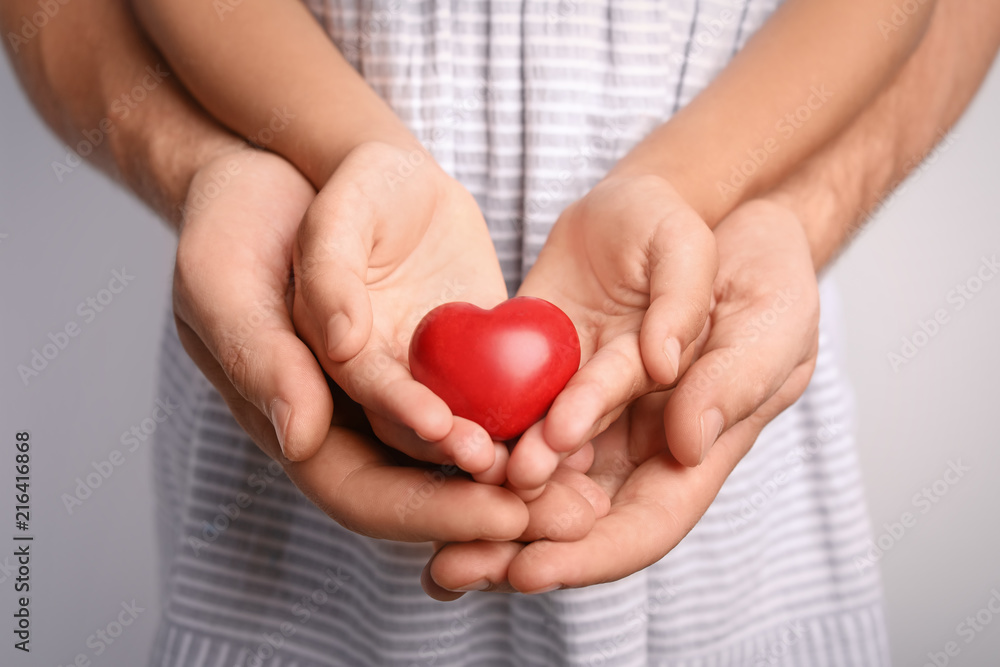 Family holding small red heart in hands together, closeup Family holding small red heart in hands together, closeup