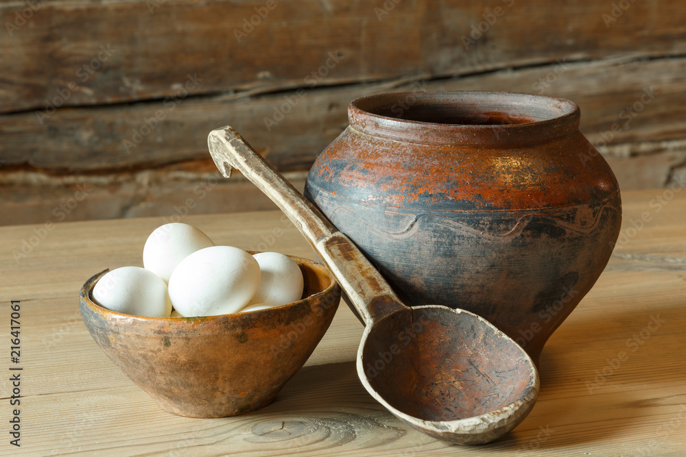A plate of eggs, a pot and a wooden spoon. A plate of eggs, a pot and a wooden spoon.