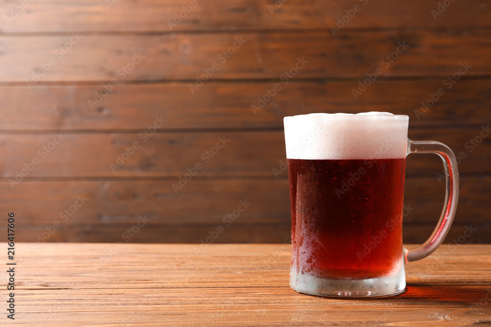 Glass mug with cold red beer on wooden table Glass mug with cold red beer on wooden table